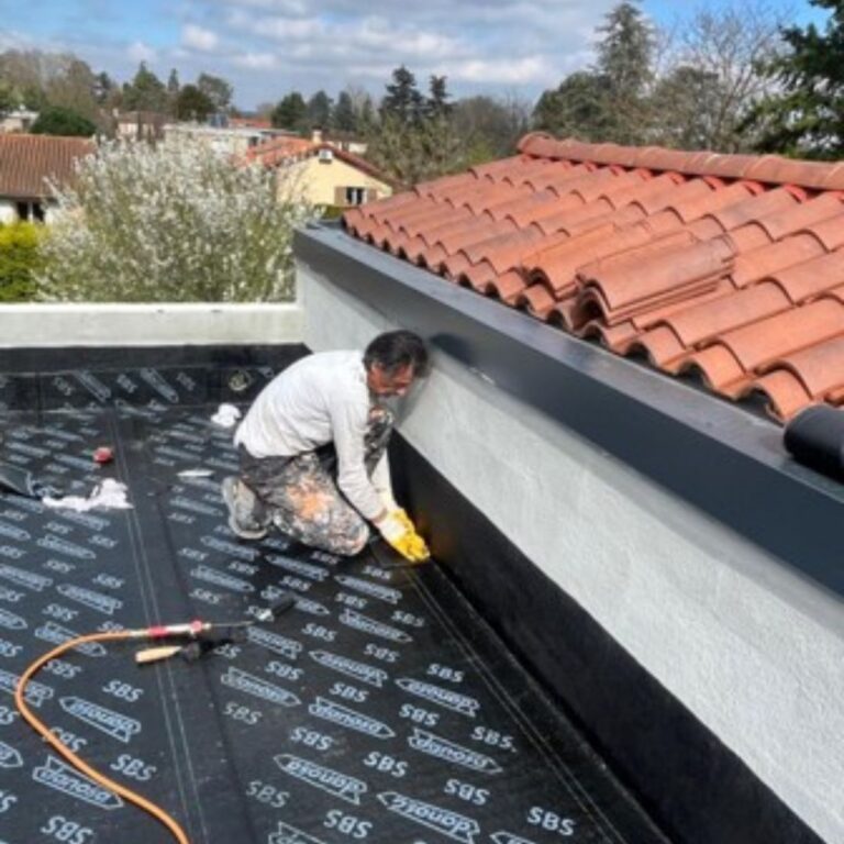 Étanchéité des bâtiments, toiture plate : Notre artisan installe soigneusement une membrane EPDM sur le toit d'un garage.