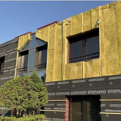Façade d’un bâtiment en rénovation avec isolation thermique par l’extérieur : panneaux de laine minérale et pare pluie posés avant finition.