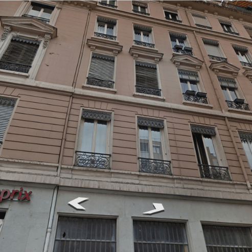 Immeuble d’angle style haussmannien à rénover, façades salies, corniches et modénatures abîmées, garde-corps en fer forgé — ravalement de façade à Lyon.