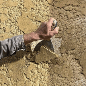 L'artisan retire le crépit vieillissant de la façade pour un rafraichissement