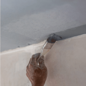 Peintre professionnel appliquant une peinture au pinceau sur l’angle mur-plafond d’une pièce — préparation et finition soignée en rénovation intérieure.