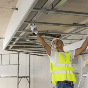 Plaquiste posant une ossature métallique pour plafond suspendu en rénovation intérieure